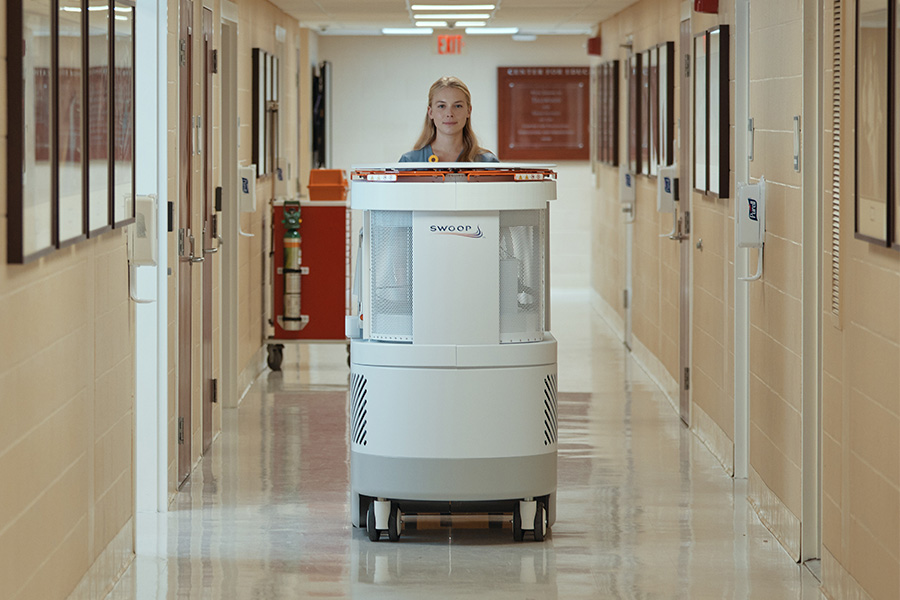 A nurse driving the Swoop® AI-powered portable MR imaging system through a hallway.